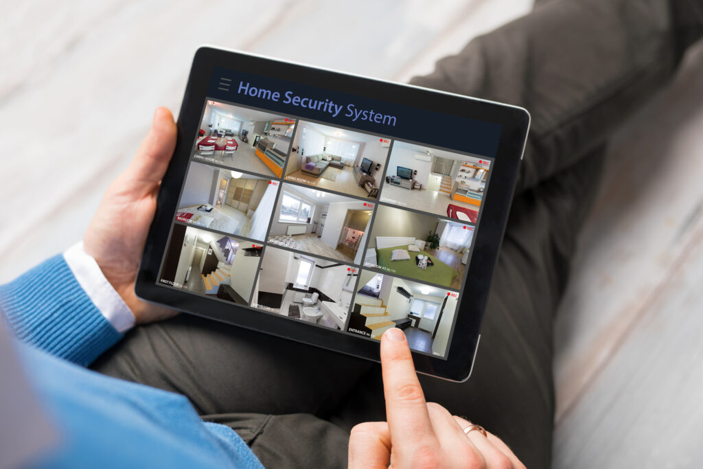 Picture of a person holding an Ipad with CCTV view of a house