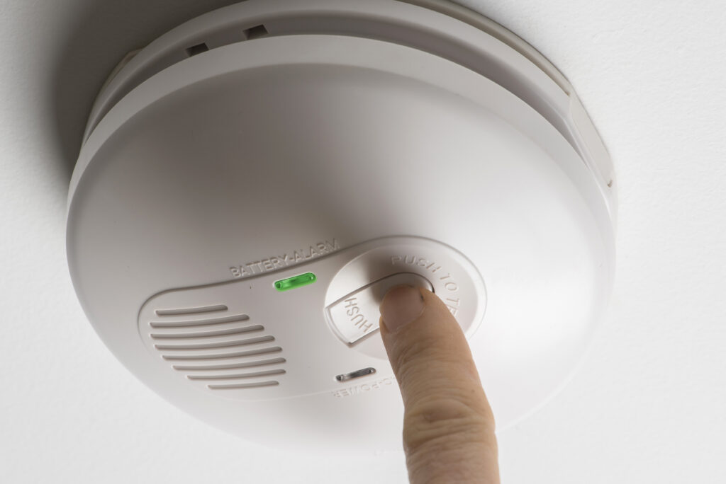 Picture of a finger pressing a button on a carbon monoxide detector