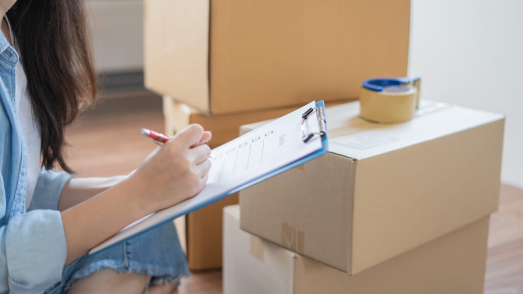 Picture of a woman ticking things off on a clipboard with boxes in the background