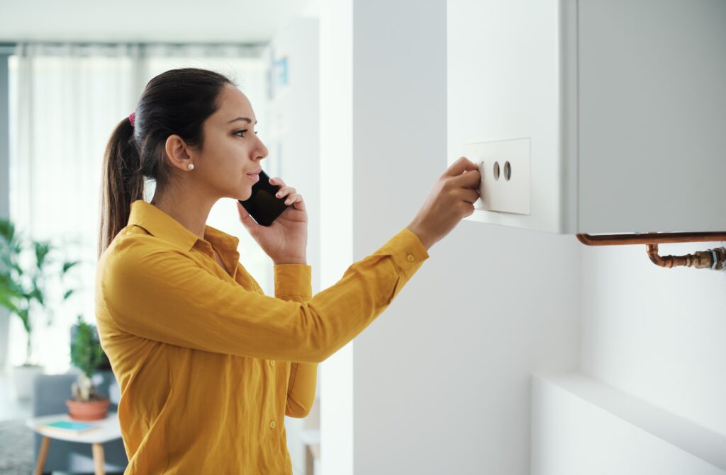 Picture of a worried woman on the phone with a hand on her boiler