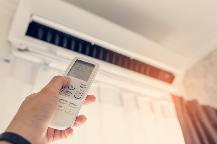 Picture of a person using a remote to adjust air conditioning unit