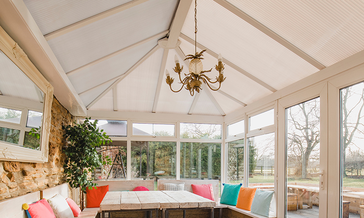 Picture of a large conservatory with colourful pillows on white sofas 