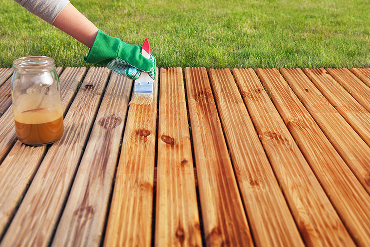 Picture of a person maintaining a garden deck by applying protective varnish