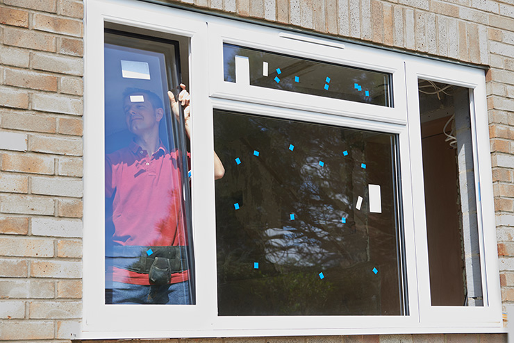 Picture of a window replacement by a tradesperson in a red shirt