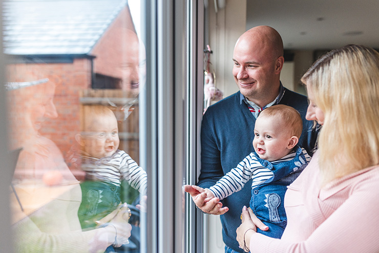 Picture of parents and a baby looking out of a window