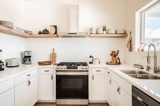 A small kitchen with white cabinets and open shelving