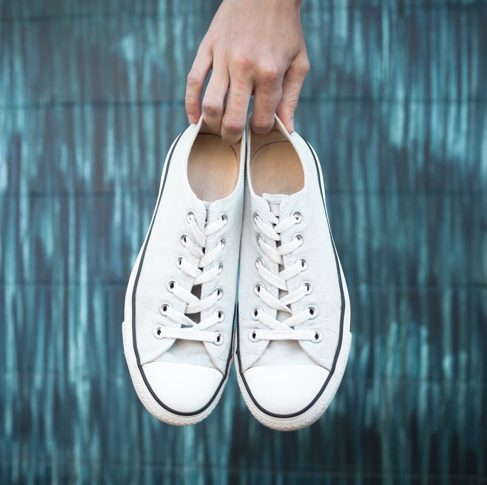 how to clean white shoes, hand holding a pair of shoes