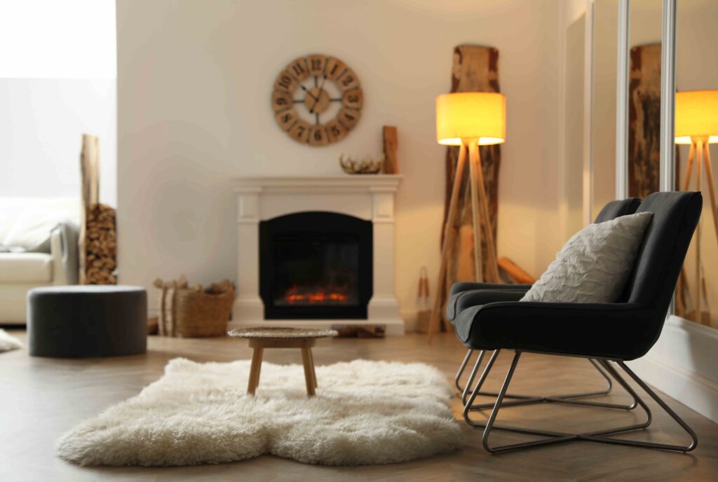 Picture of a living room with a lit fireplace and white rug next to a black sofa