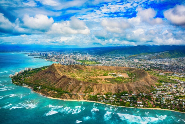 The beautiful coastline of Honolulu Hawaii shot from an altitude of about 1000 feet during a helicopter photo flight over the Pacific Ocean with Diamond Head in the foreground.