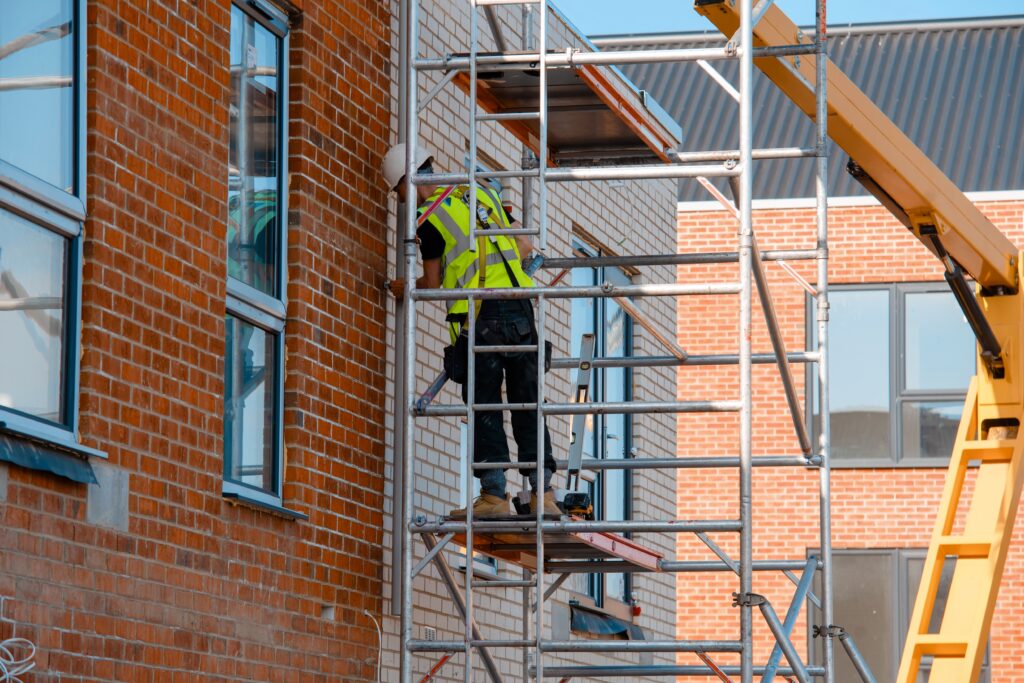 Picture of a man constructing scaffolding in white helmet